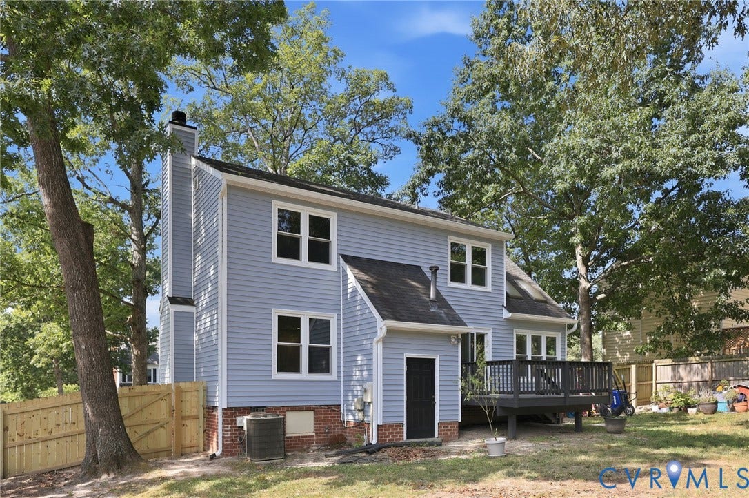 9500 Mesquite Road, Glen Allen, VA 23060 Rear exterior featuring light blue siding, a dark grey deck with black railings, a full privacy fence with gate, and mature trees