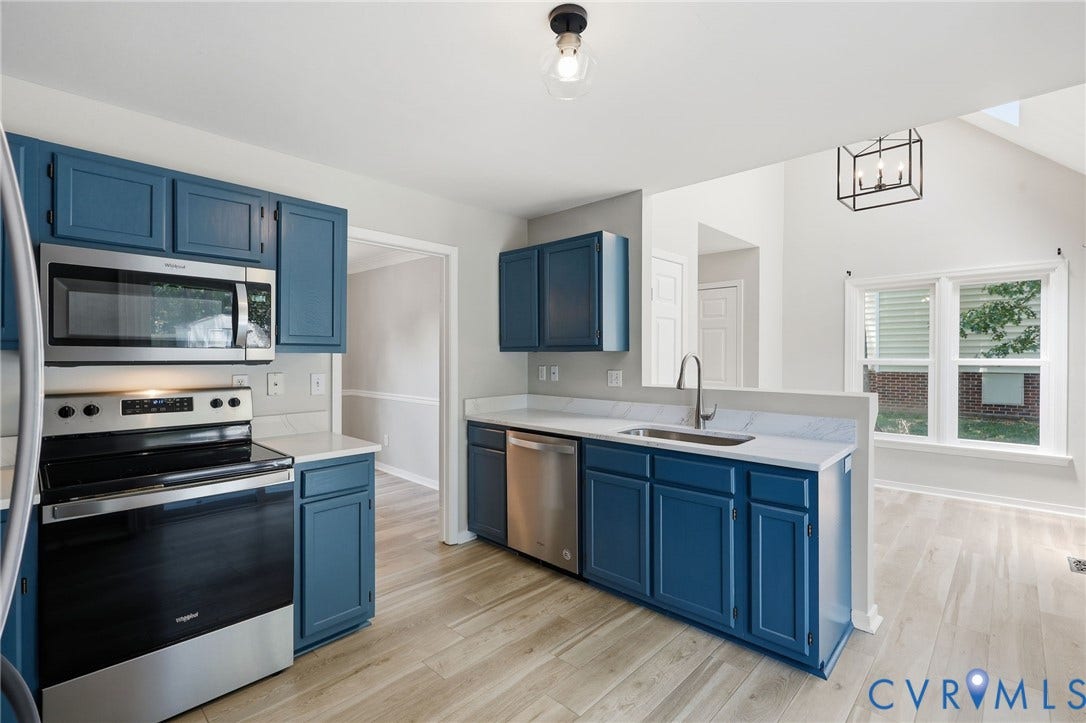 9500 Mesquite Road, Glen Allen, VA 23060 Open-concept kitchen featuring blue cabinetry, light-toned wood-finish flooring, white countertops, and stainless steel appliances including an oven range, microwave, and dishwasher