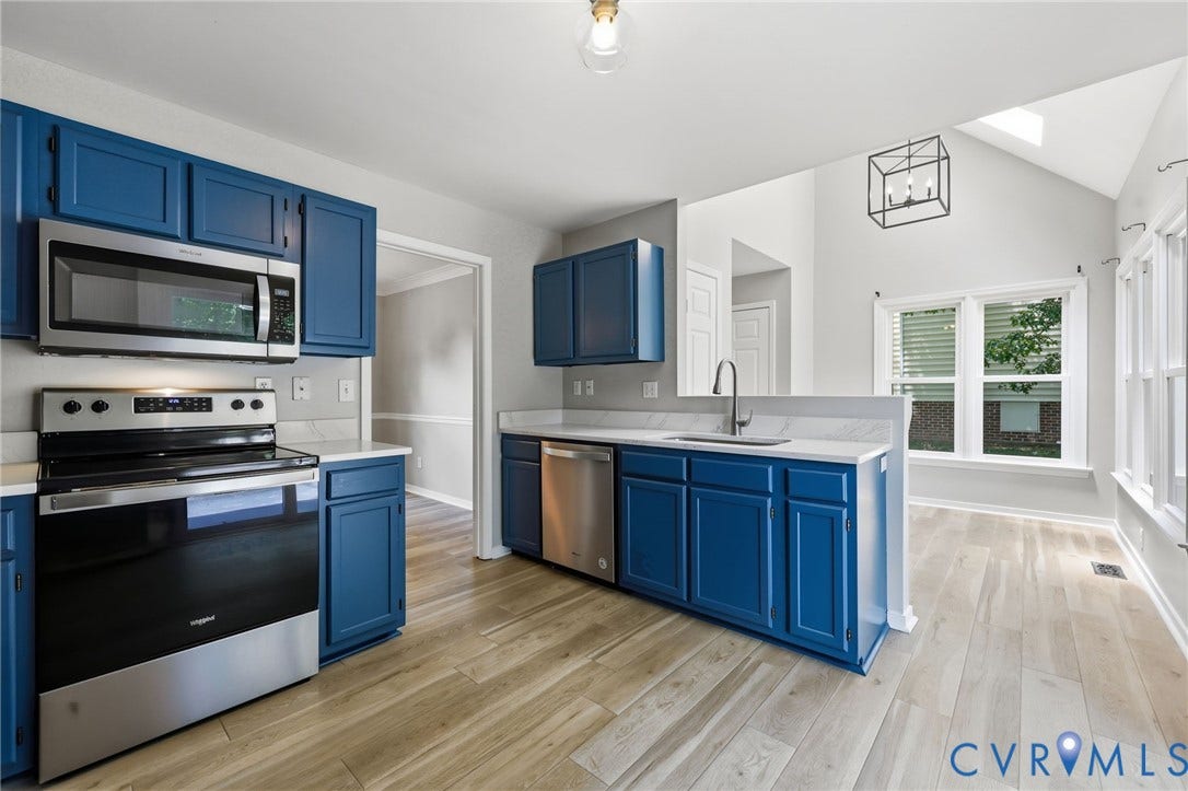 9500 Mesquite Road, Glen Allen, VA 23060 Open-concept kitchen featuring blue cabinetry, light wood-finish flooring, stainless steel appliances, white countertops, and vaulted ceilings