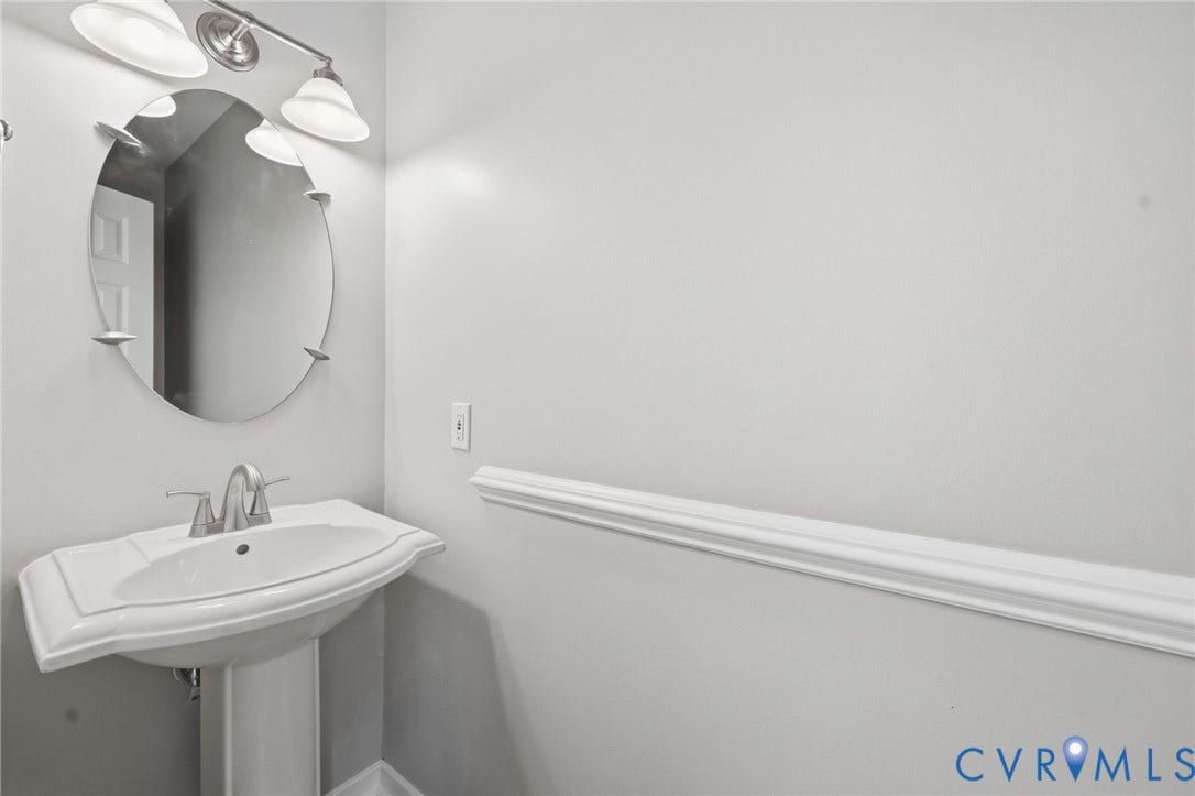 9500 Mesquite Road, Glen Allen, VA 23060 Pedestal sink with a two-handle faucet, illuminated by a three-bulb vanity light fixture