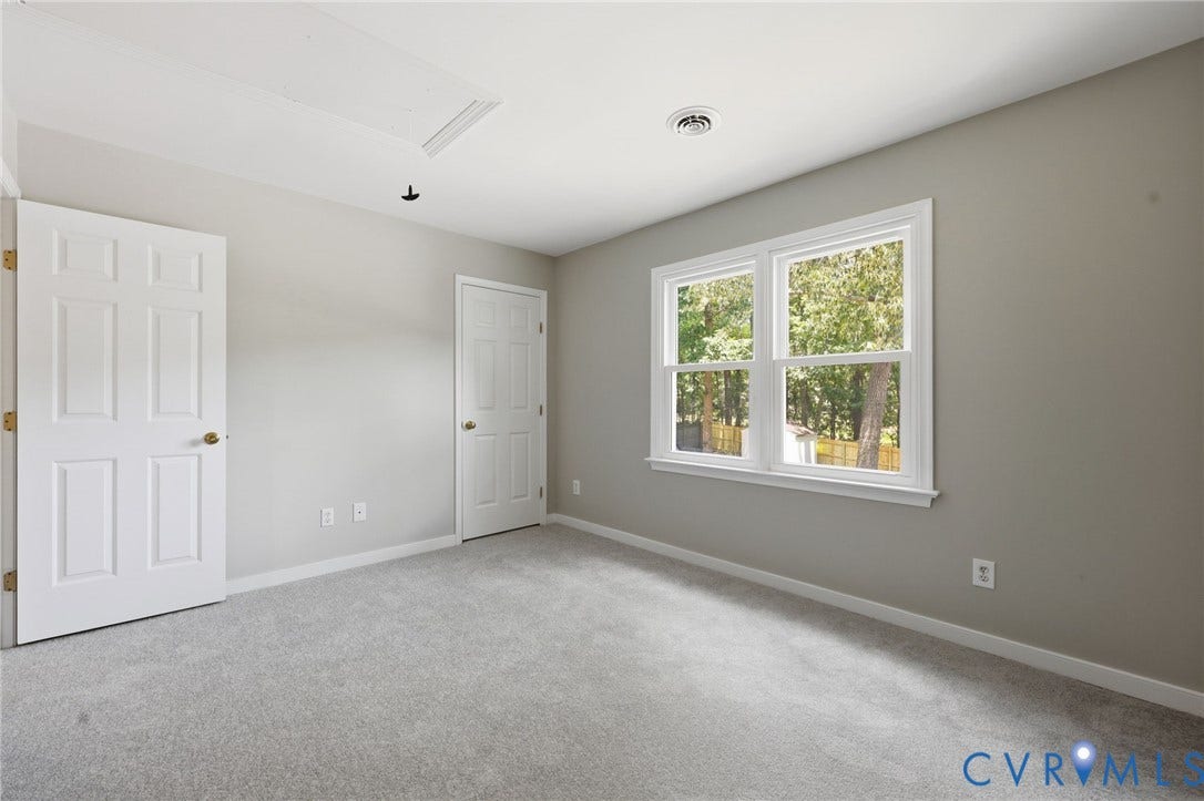 9500 Mesquite Road, Glen Allen, VA 23060 Neutral-toned room featuring a double window with white trim, two white six-panel doors with brass-toned hardware, light gray carpeting, and white baseboards