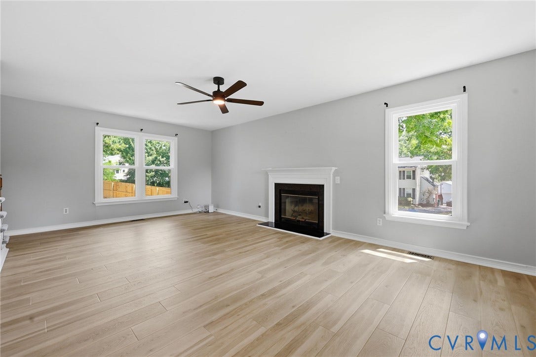 9500 Mesquite Road, Glen Allen, VA 23060 Spacious room featuring wood-finish flooring, a contemporary ceiling fan, and a fireplace with a white mantel and black surround