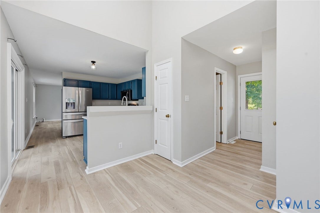 9500 Mesquite Road, Glen Allen, VA 23060 Entryway featuring light wood-finish flooring extending into the kitchen, kitchen with blue cabinetry, stainless steel refrigerator, and ample counter space, kitchen with recessed lighting, and white walls throughout