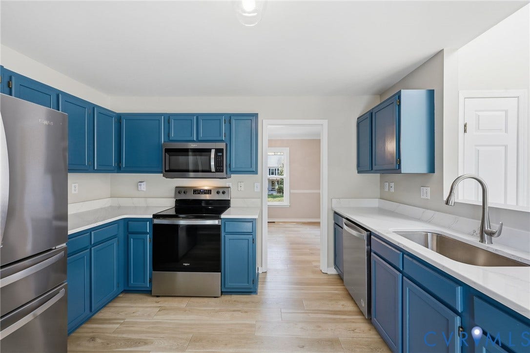9500 Mesquite Road, Glen Allen, VA 23060 Kitchen featuring blue cabinetry, light-toned countertops, wood-finish flooring, and stainless-steel appliances including a refrigerator, range, microwave, and dishwasher