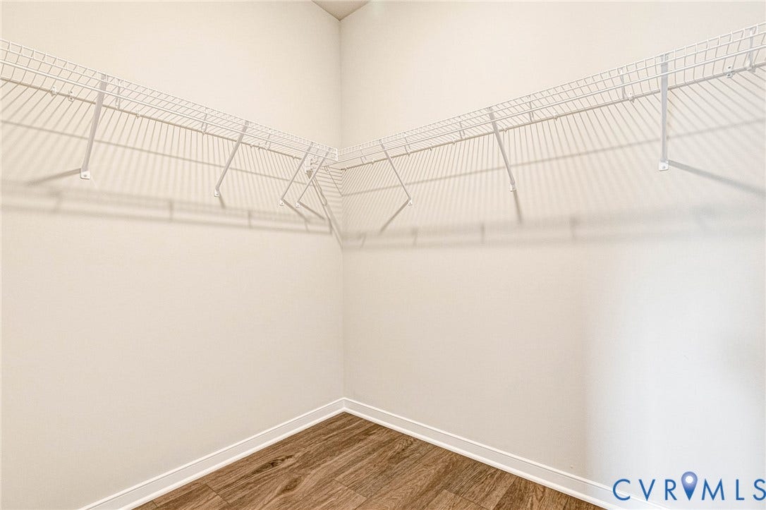 Walk-in closet featuring white wire shelving, white walls, and wood-finish flooring