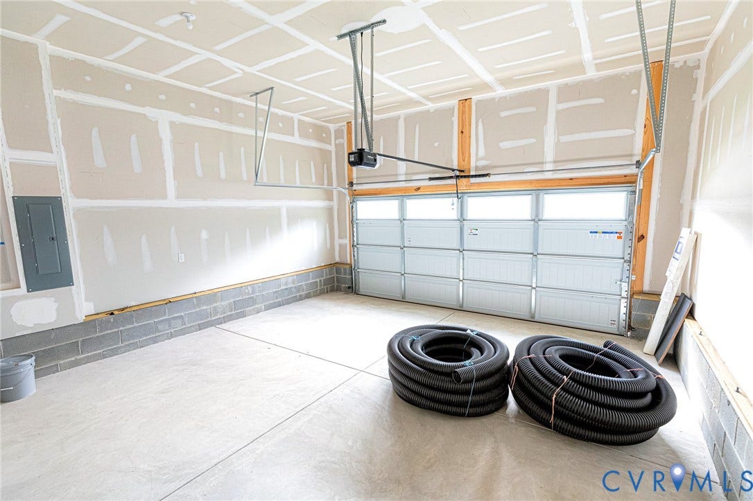 Garage space featuring a concrete floor, exposed wood framing, and a sectional garage door with upper-level window panels