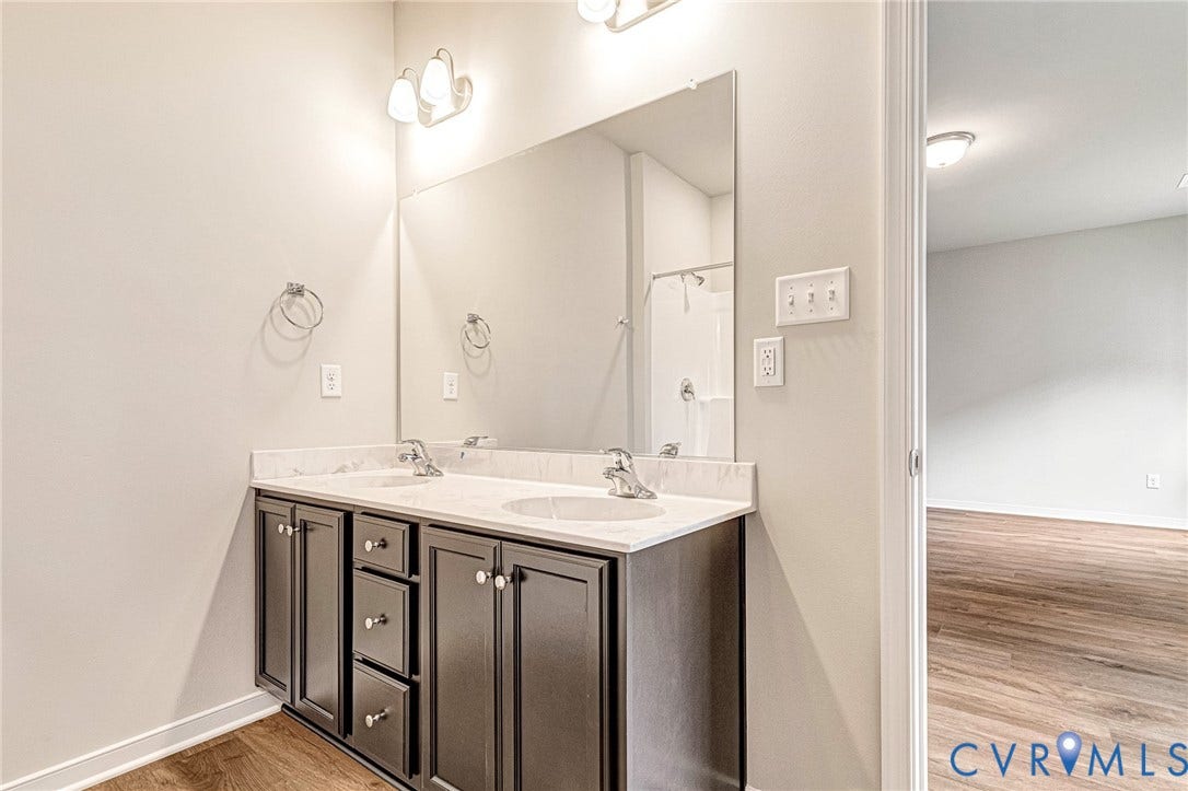 Double vanity featuring dark wood-finish cabinetry, white countertops, and dual undermount sinks