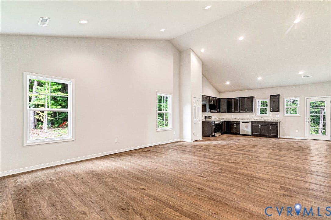 Open-concept living area featuring wood-finish flooring, recessed lighting, and vaulted ceilings