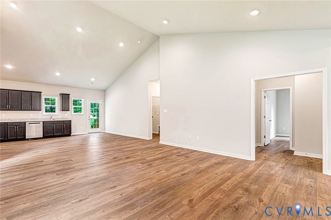Spacious living area featuring wood-finish flooring and a high vaulted ceiling with recessed lighting