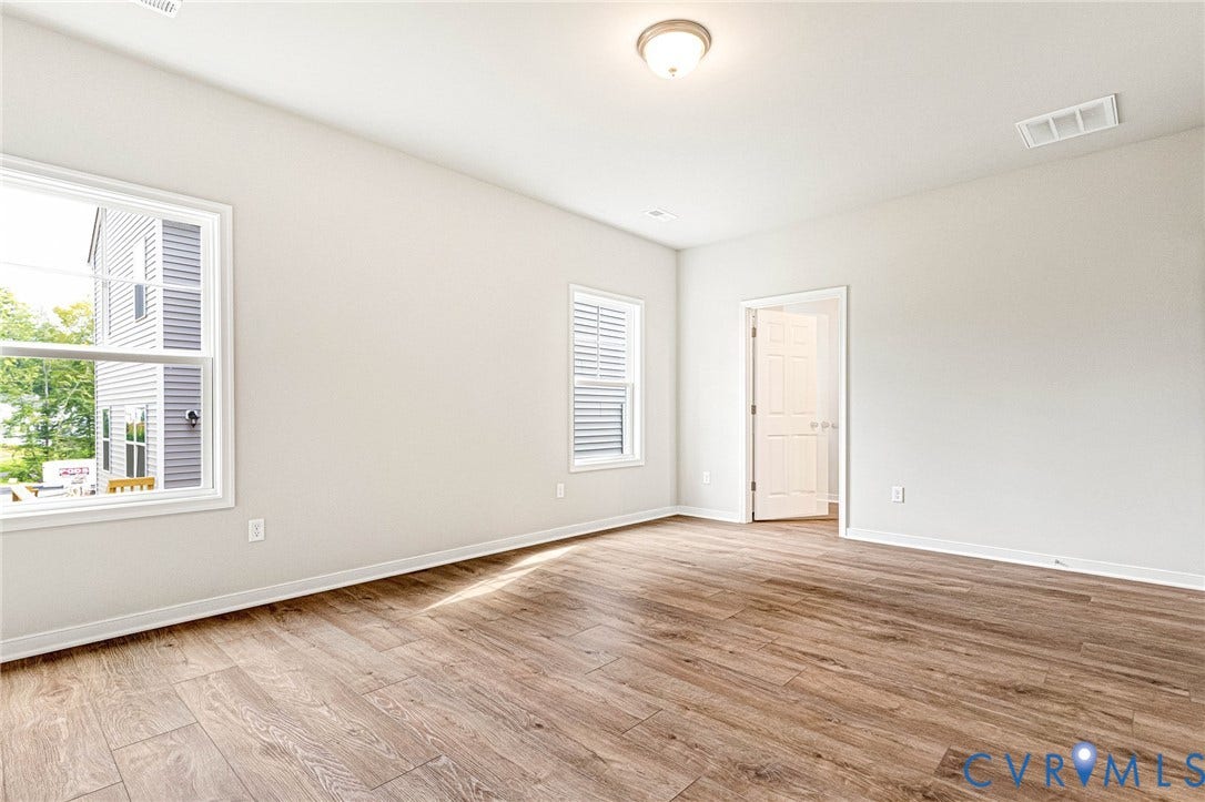 Spacious room featuring wood-finish flooring and neutral wall tones