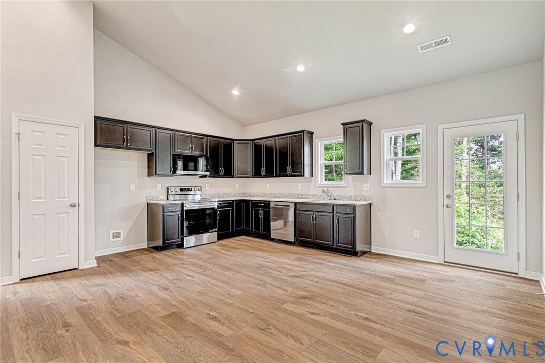 Spacious open-concept kitchen featuring dark wood cabinetry, granite-finish countertops, and stainless steel appliances