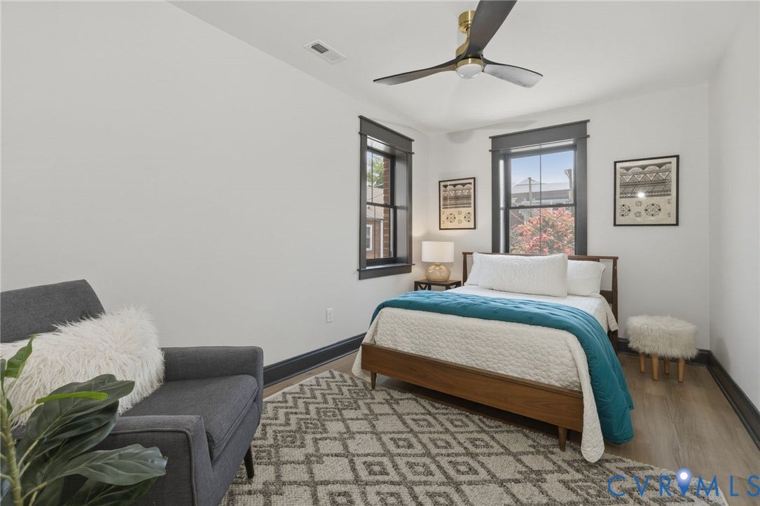 2627 Kensington Avenue, Museum District, Richmond, VA 23220 Bedroom featuring wood-finish flooring, two windows with dark trim, dark baseboards, and a ceiling fan with gold-tone accents