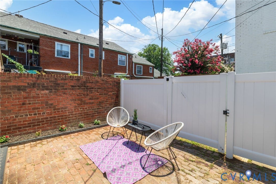 2627 Kensington Avenue, Museum District, Richmond, VA 23220 Brick paved patio area featuring a privacy fence, mature flowering tree, and a brick retaining wall
