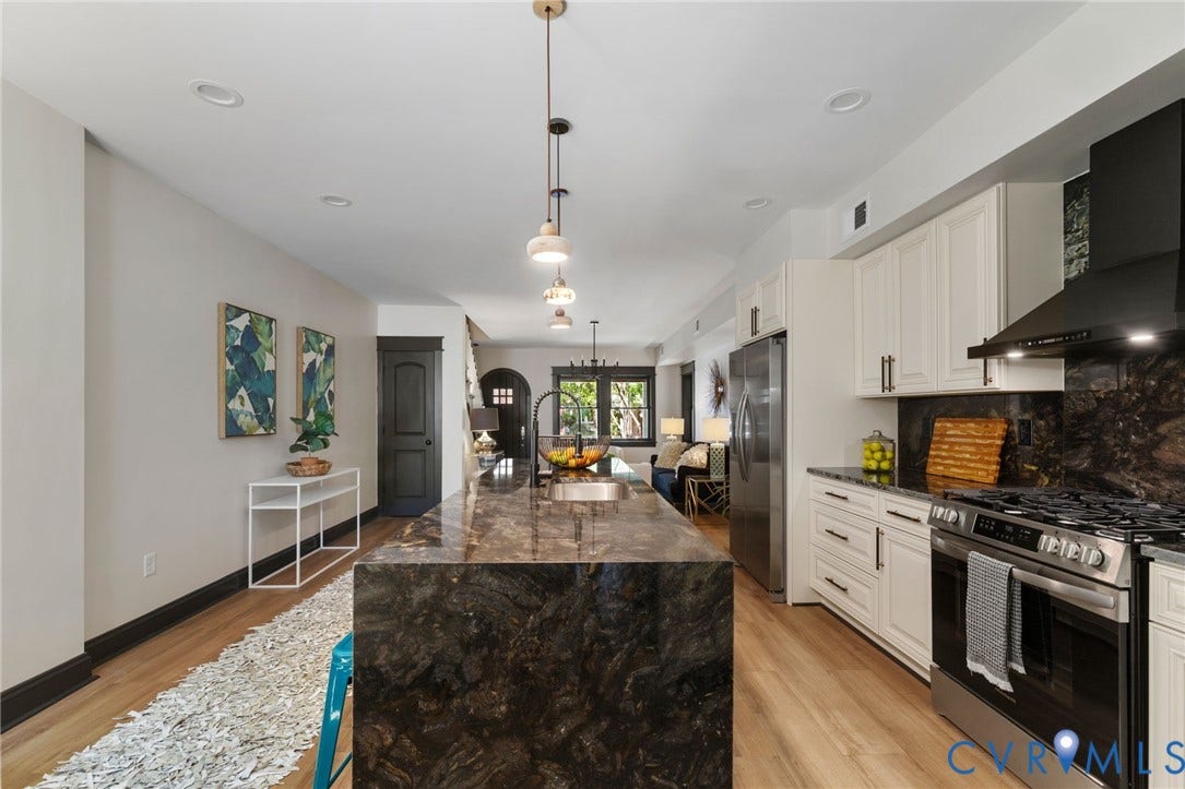 2627 Kensington Avenue, Museum District, Richmond, VA 23220 Kitchen featuring a large waterfall island with an undermount sink, white cabinetry, dark stone countertops and backsplash, stainless steel appliances, and wood-finish flooring