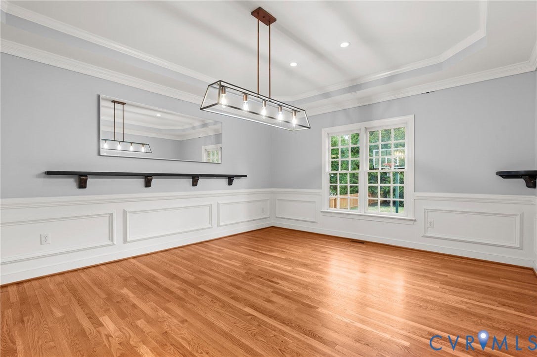 Hardwood flooring complements the decorative wainscoting and crown molding