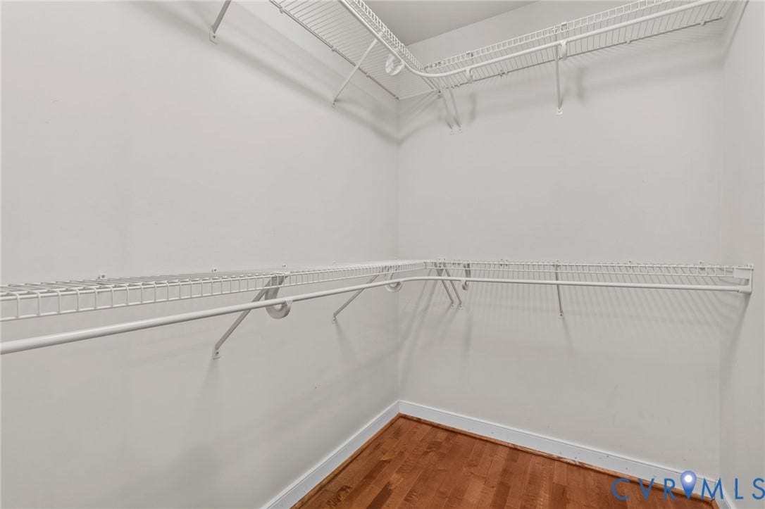 Walk-in closet with white wire shelving and hanging rods