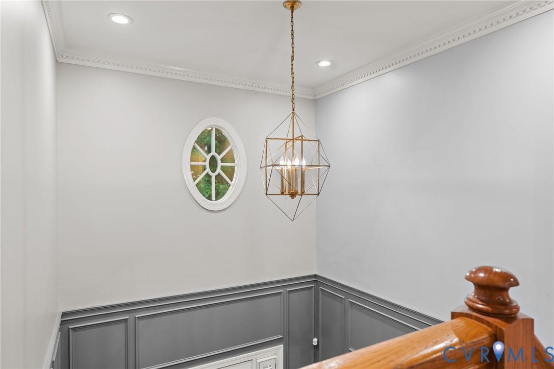 Recessed lighting, crown molding, and wainscoting details complement the geometric chandelier