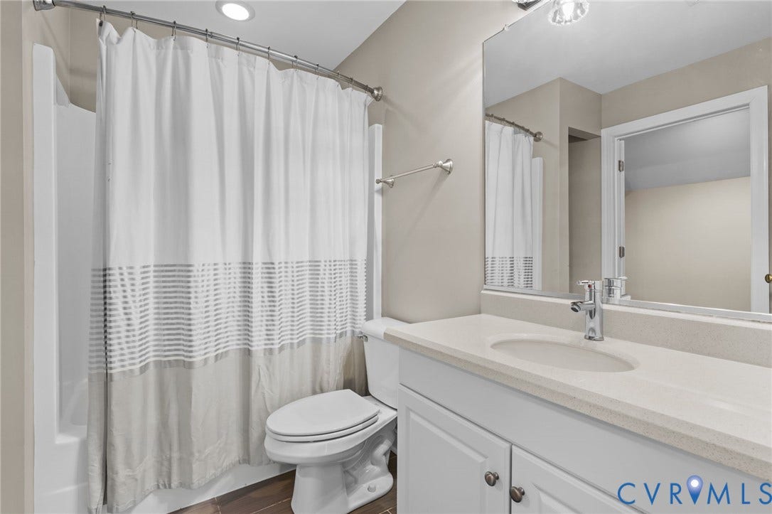 Bathroom featuring a built-in vanity with white cabinetry, an integrated sink, and a light-toned countertop