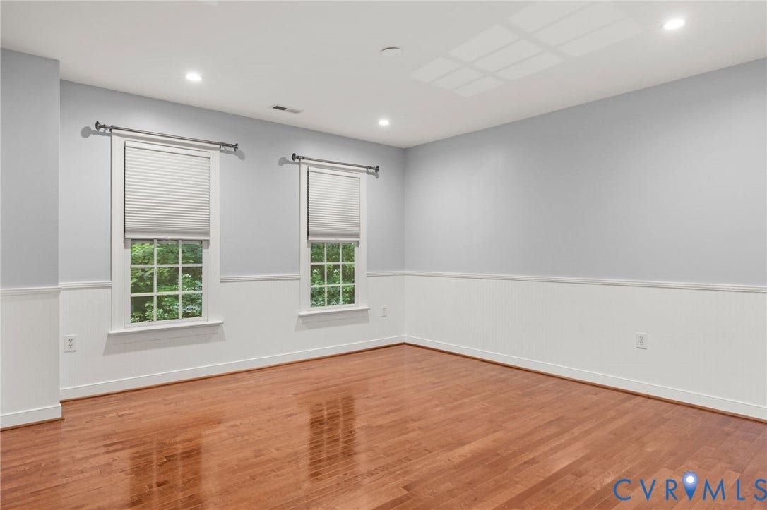 Room featuring wood-finish flooring, white wainscoting, recessed lighting, and two windows with blinds