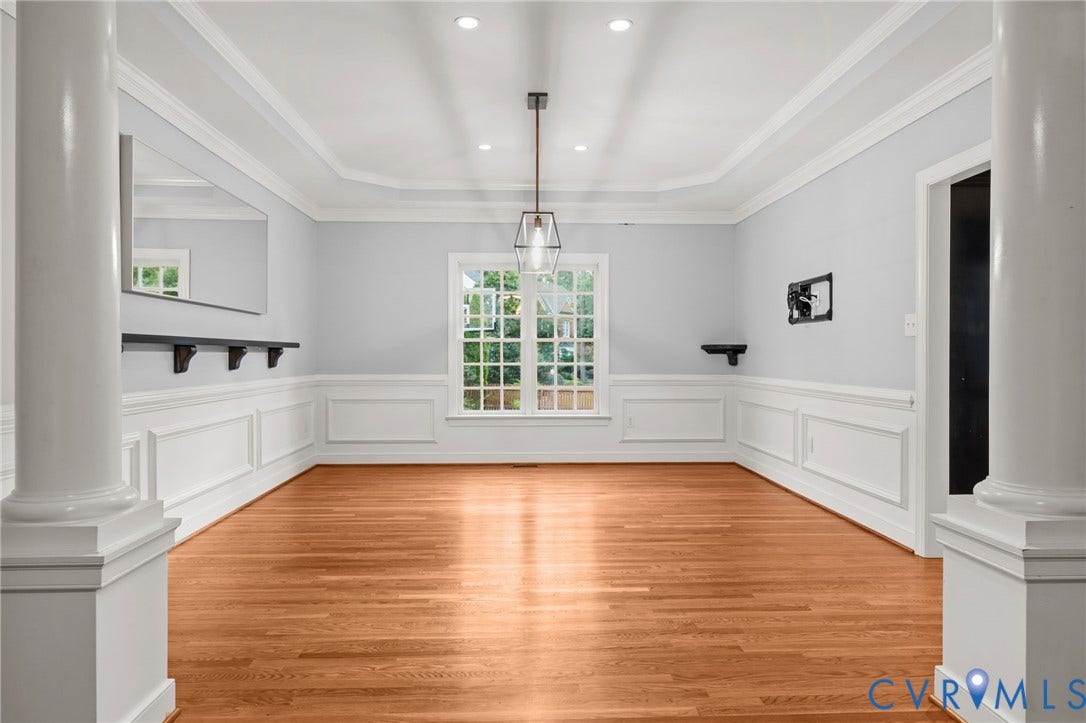 Spacious room featuring wood-finish flooring, wainscoting, and crown molding
