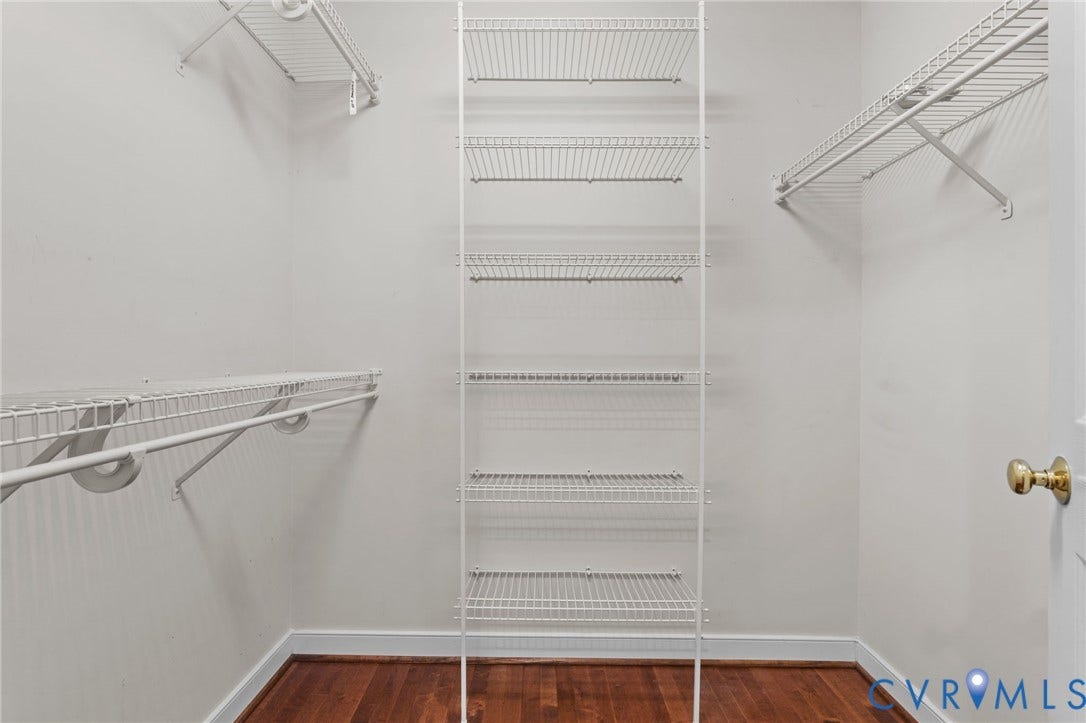 Walk-in closet featuring multiple wire shelving units, white walls, and wood-finish flooring