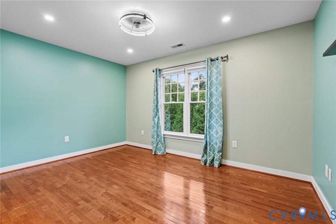 Hardwood flooring throughout this room featuring a window with white trim, recessed lighting, and a ceiling-mounted light fixture