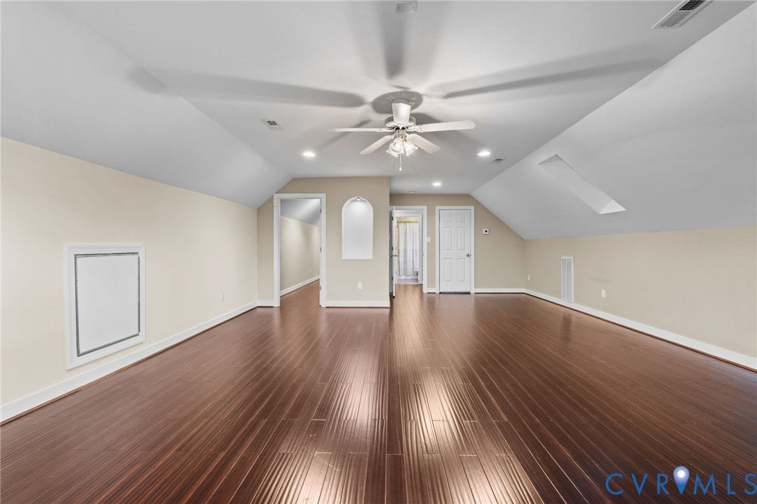 Spacious upper-level room featuring rich wood-finish flooring, recessed lighting, and a ceiling fan