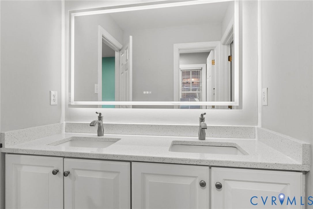 Dual vanity featuring integrated sinks, speckled countertops, and white shaker-style cabinetry