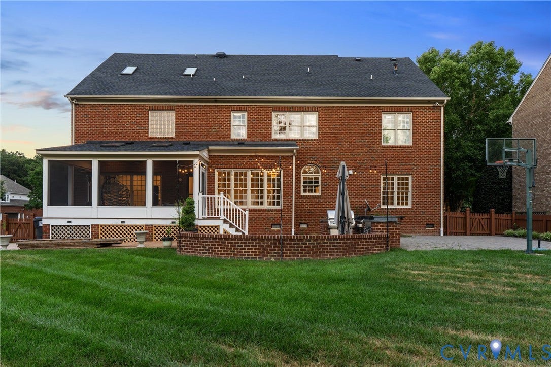 Rear exterior featuring a brick facade, screened porch, and an elevated brick patio with a white railing