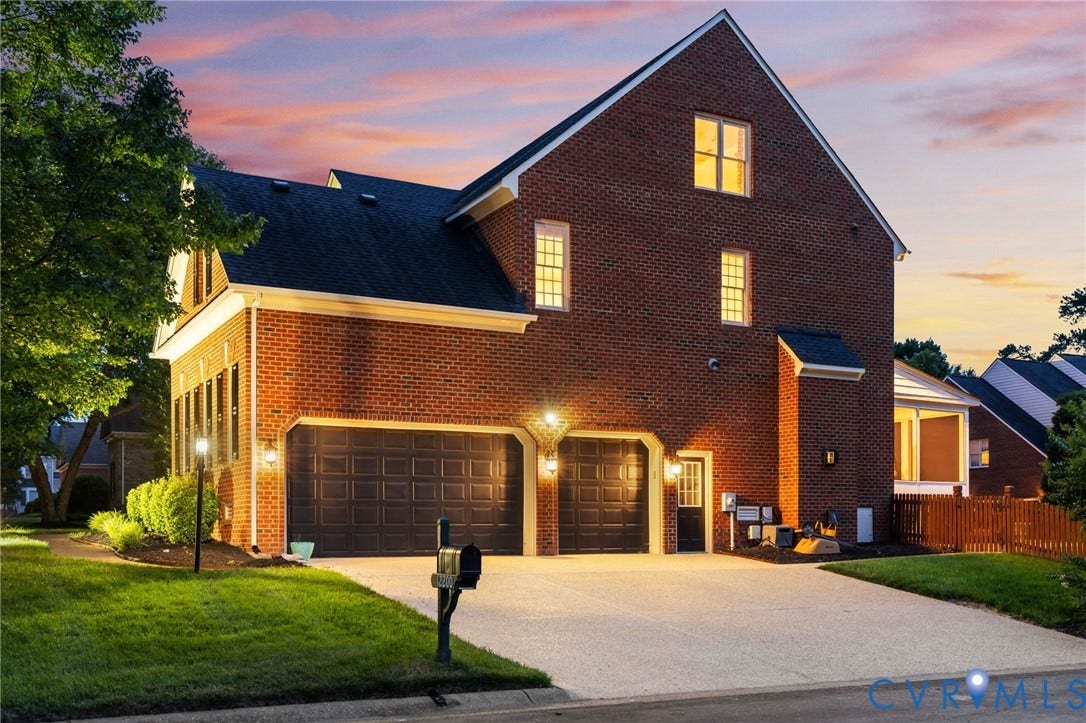Brick exterior featuring a two-car garage, a concrete driveway, and a front entry door with an overhead light fixture