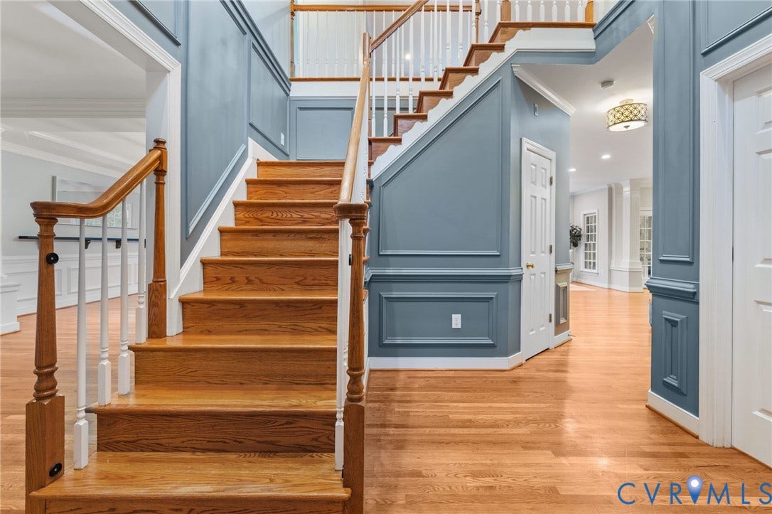 Grand staircase featuring wood-finish treads, white risers, and wood-finish railings with white balusters