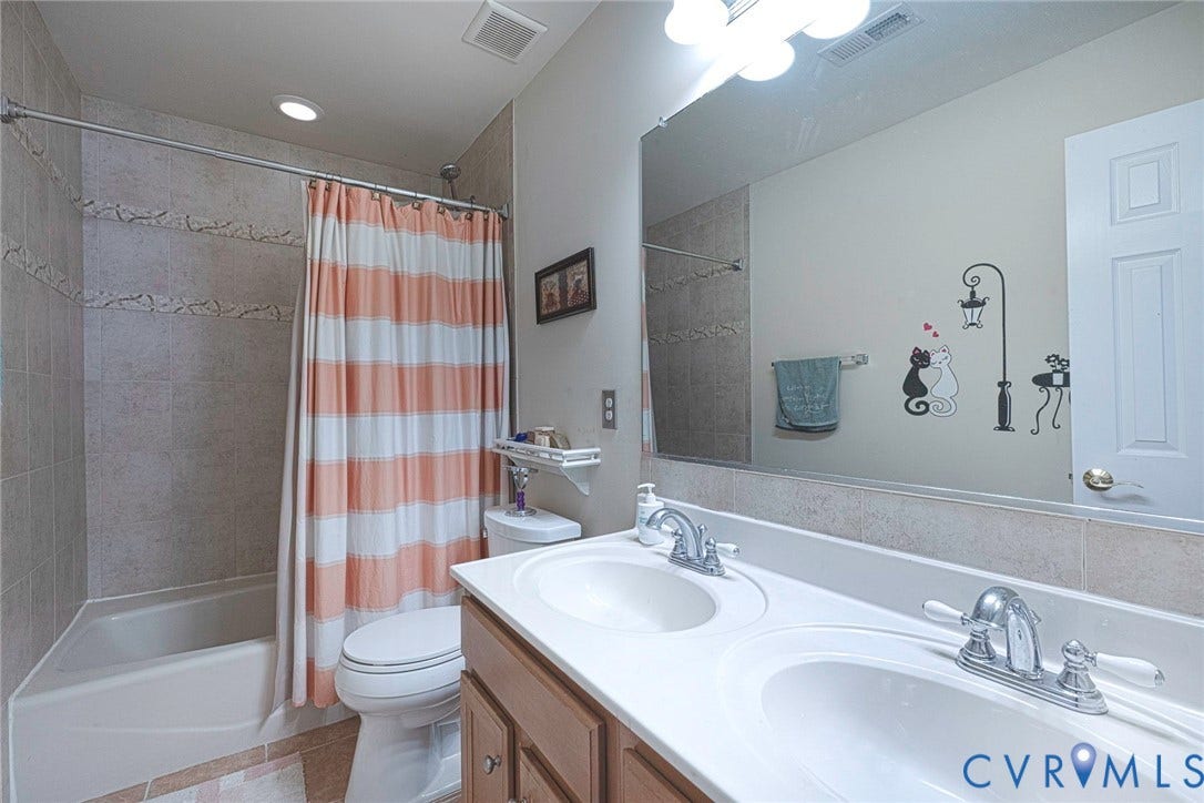 1900 Brilland Court, Glen Allen, VA 23060 Bathroom featuring a dual-sink vanity with chrome fixtures, a full-width mirror, and a combination tub/shower with tiled walls