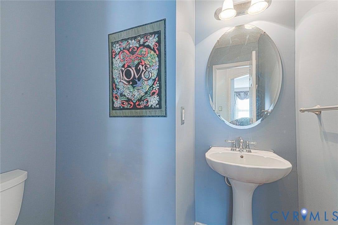 1900 Brilland Court, Glen Allen, VA 23060 Pedestal sink with a dual-handle faucet, oval mirror, and a wall-mounted light fixture