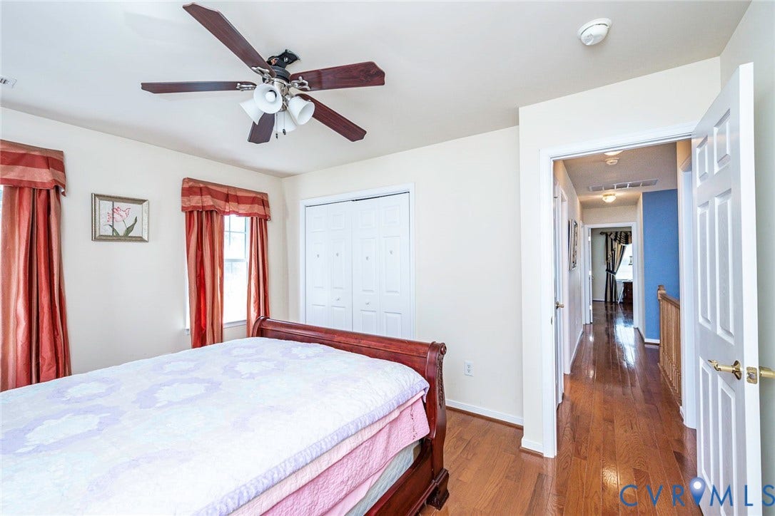1900 Brilland Court, Glen Allen, VA 23060 Bedroom 3 featuring wood-finish flooring, two windows with red drapes, a ceiling fan with integrated lighting, and white bi-fold closet doors