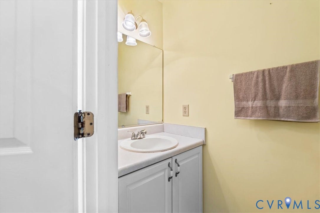 2924 Warfield Ridge Terrace, Chester, VA 23831 Bathroom vanity featuring a white countertop with an integrated sink, dual-door cabinetry, and a wall-mounted mirror
