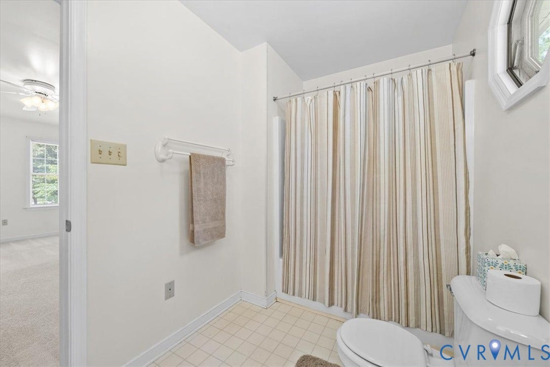 2924 Warfield Ridge Terrace, Chester, VA 23831 Bathroom featuring a shower with a striped curtain, a white toilet, and a hexagonal window