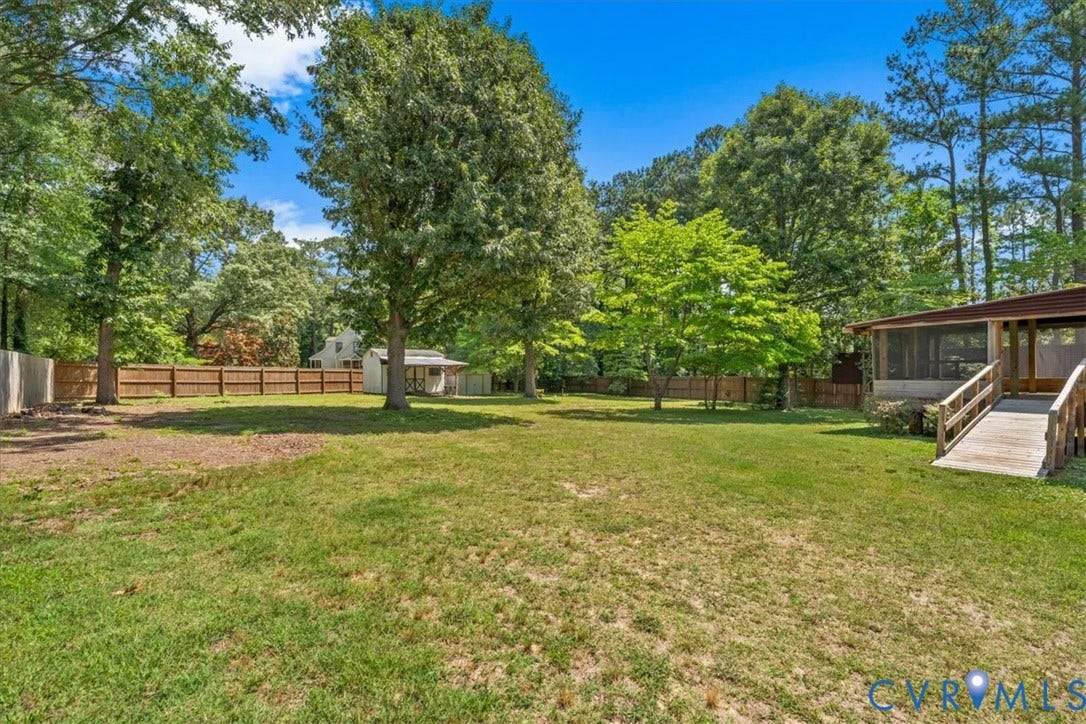 2924 Warfield Ridge Terrace, Chester, VA 23831 Expansive backyard featuring a large grassy area, mature trees, a wood privacy fence, a screened porch with a wood ramp, and an outbuilding