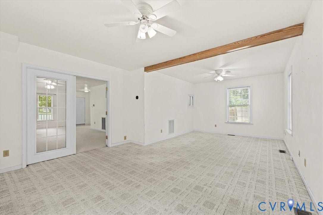 2924 Warfield Ridge Terrace, Chester, VA 23831 Spacious interior with neutral patterned carpeting, white walls, exposed wood beam, multiple ceiling fans, and a glass-paned door