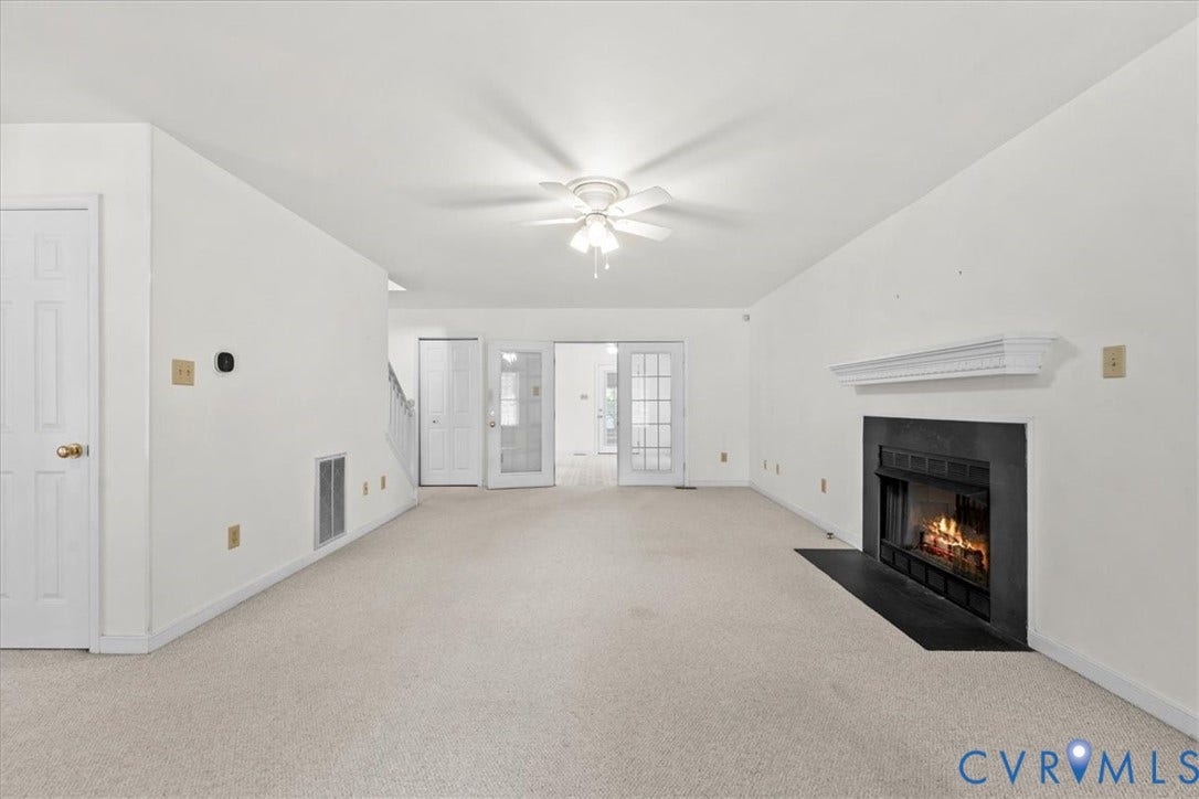 2924 Warfield Ridge Terrace, Chester, VA 23831 Carpeted living area featuring a central ceiling fan, a black fireplace with a white mantel, and a pair of French doors