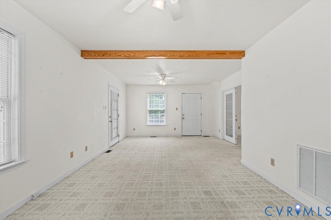 2924 Warfield Ridge Terrace, Chester, VA 23831 Spacious room featuring patterned carpeting, multiple windows, a wood beam ceiling accent, and two ceiling fans
