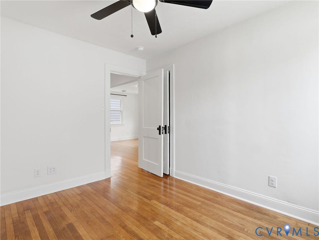 Bright interior room featuring wood-finish flooring, white walls, and a ceiling fan with integrated lighting