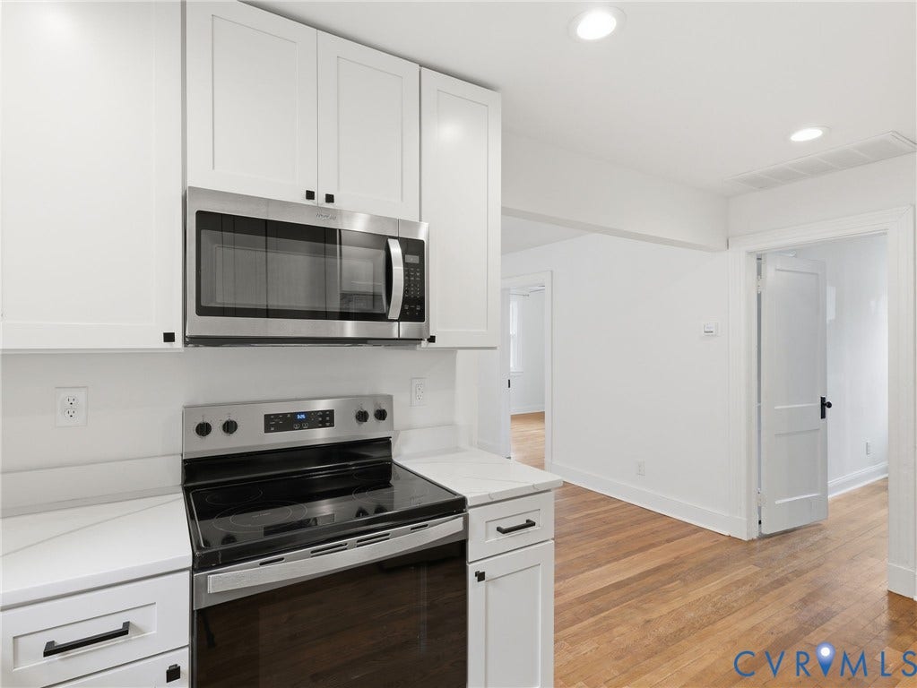 Kitchen featuring white shaker cabinetry, stainless steel microwave, stainless steel electric range, and light-toned countertops
