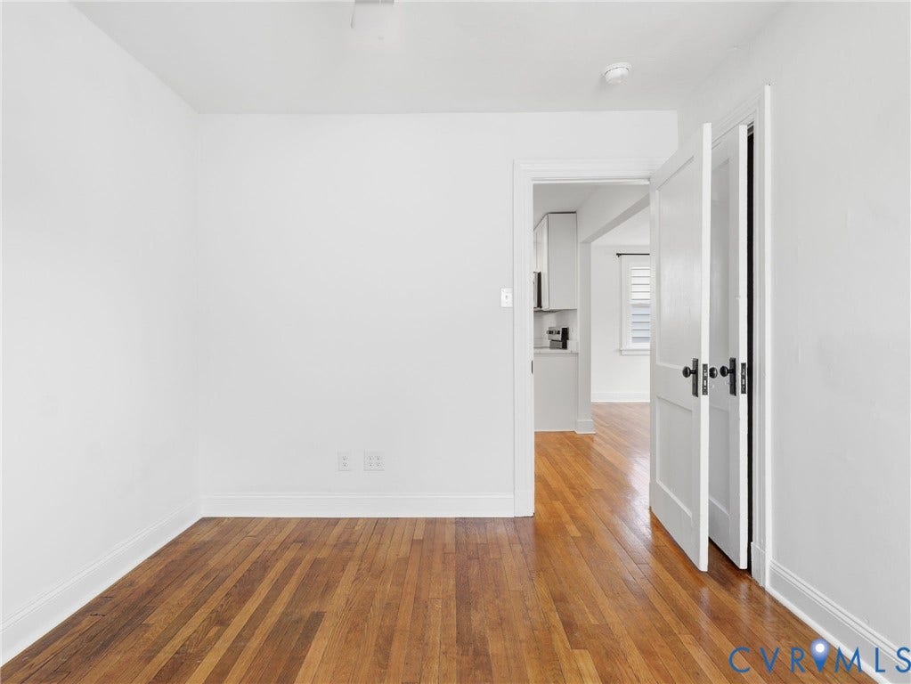 Room featuring wood-finish flooring, white baseboards, and white walls