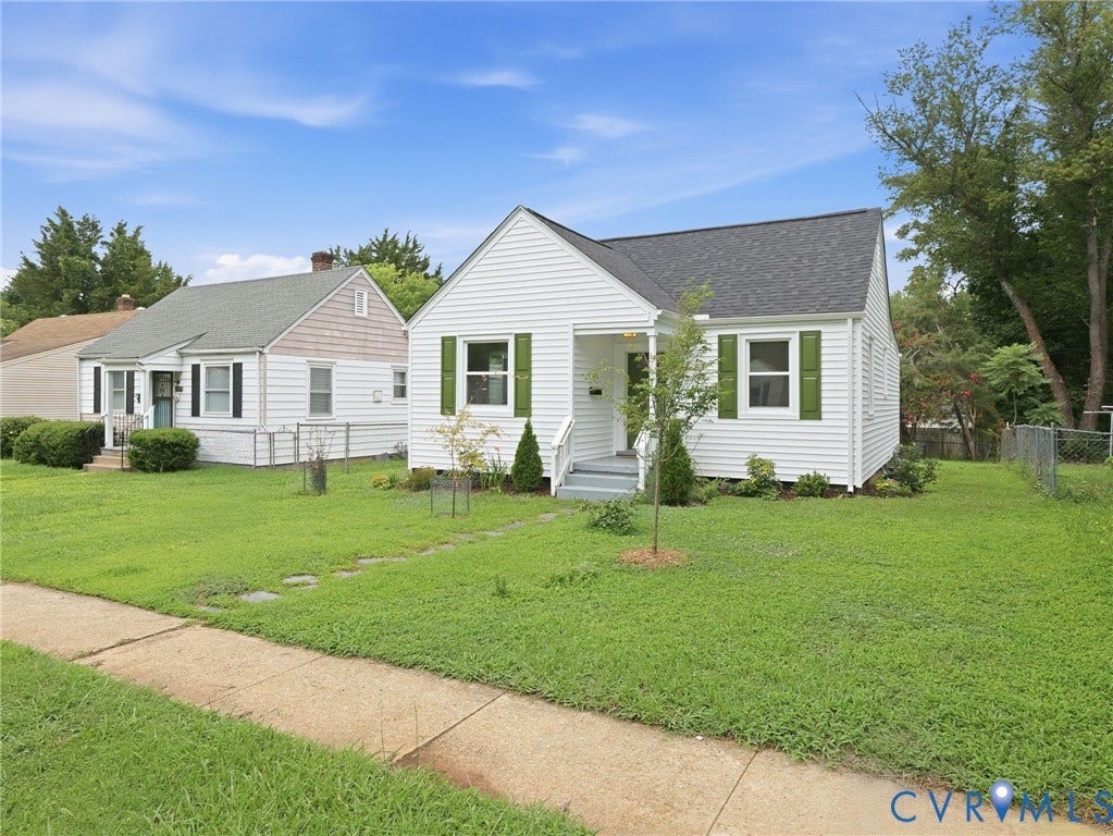 White siding home with green window shutters, a front porch, and a dark shingle roof