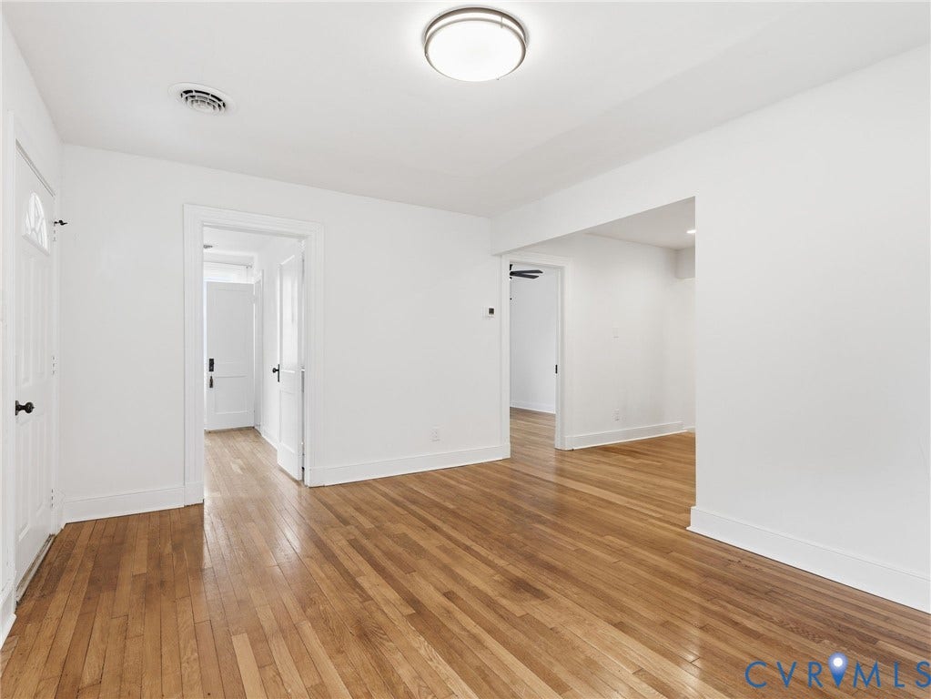Hardwood flooring throughout, white baseboards, and bright white walls