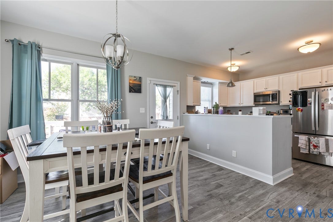 1301 Dance Street, Randolph, Richmond, VA 23220 Open-concept kitchen and dining area featuring wood-finish flooring, white cabinetry, stainless steel appliances, and a contemporary spherical chandelier