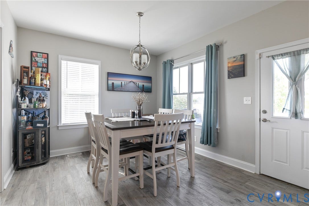 1301 Dance Street, Randolph, Richmond, VA 23220 Dining area featuring wood-finish flooring, two large windows, a white paneled door with a glass insert, and a modern spherical chandelier