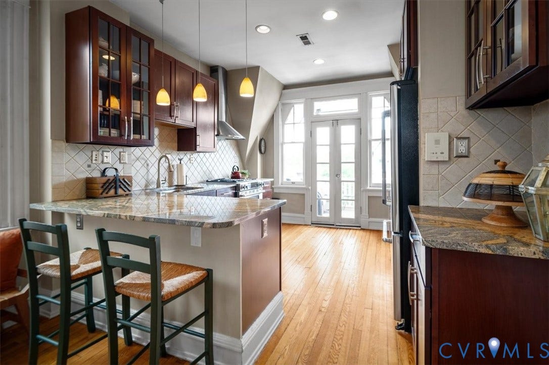 View into the Kitchen. There are several glass front upper cabinets.
