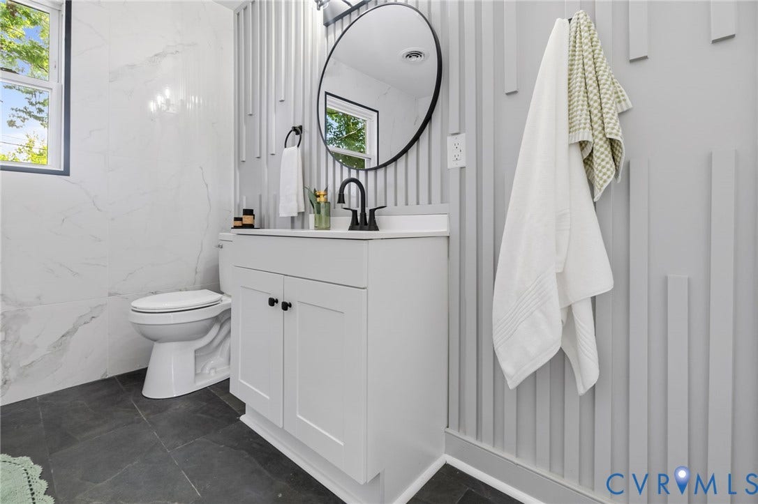 3122 Maplewood Avenue, Stadium, Richmond, VA 23221 White vanity with black hardware, black matte faucet, circular mirror, and textured wall paneling