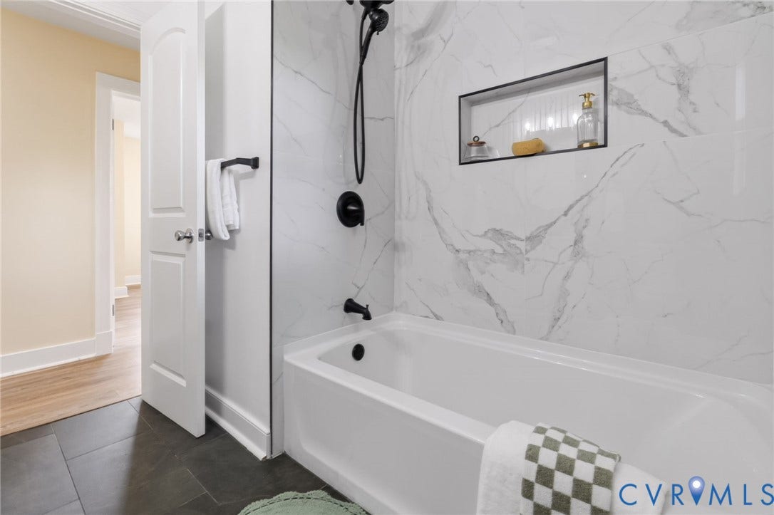 3122 Maplewood Avenue, Stadium, Richmond, VA 23221 White bathtub with matte black fixtures, marble-patterned tile surround, and a recessed shower niche